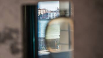 A view through a window with a reflection of buildings and a body of water.
