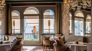A dining area with tables, chairs, and a view through large arched windows. - Ca Maria Adele (Venice)