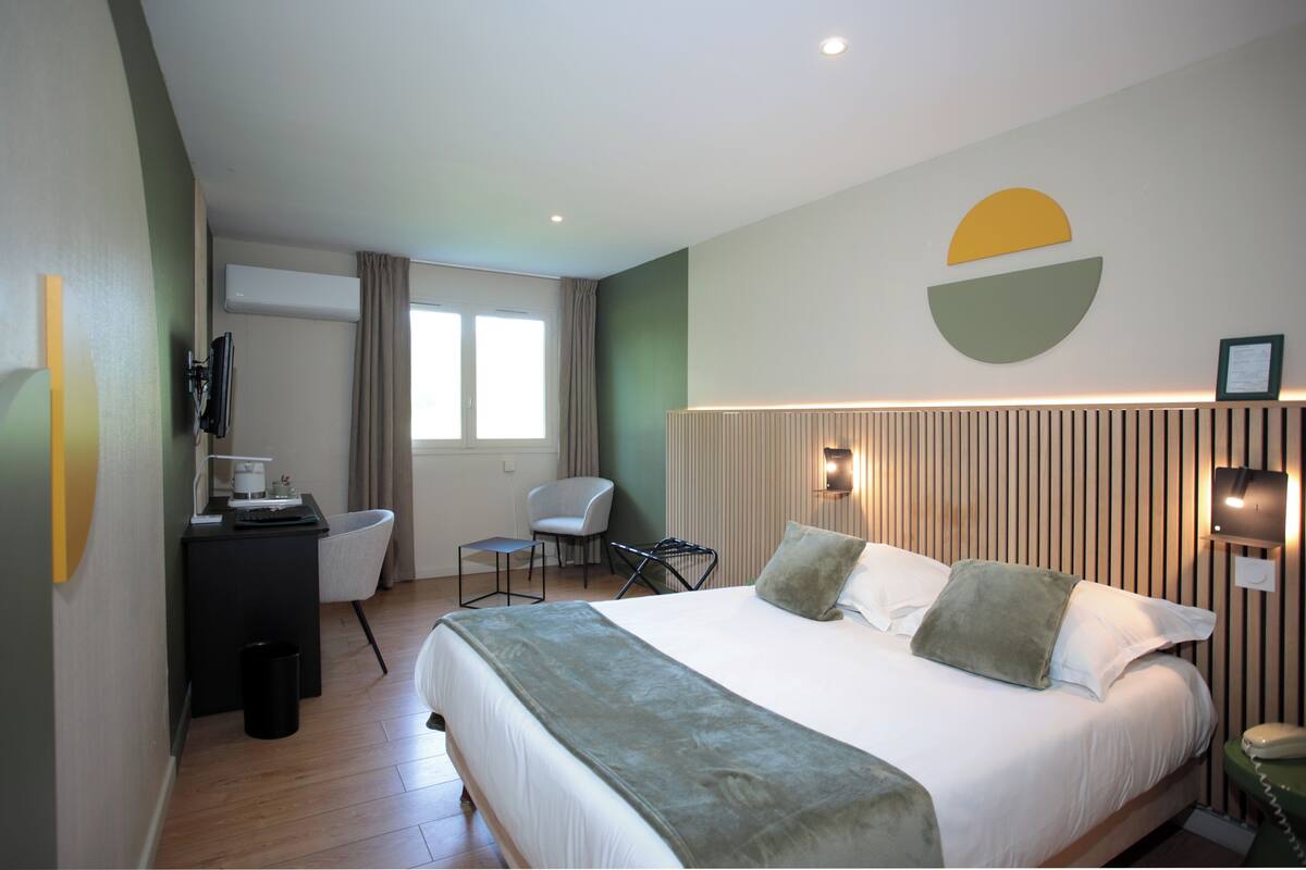 Ein Hotelzimmer mit Bett, Schreibtisch, Stuhl, Fernseher und Fenster.