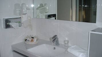 A bathroom with a white sink, a mirror, and a towel rack.