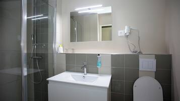 Un baño con cabina de ducha de vidrio, un lavabo blanco y un inodoro.