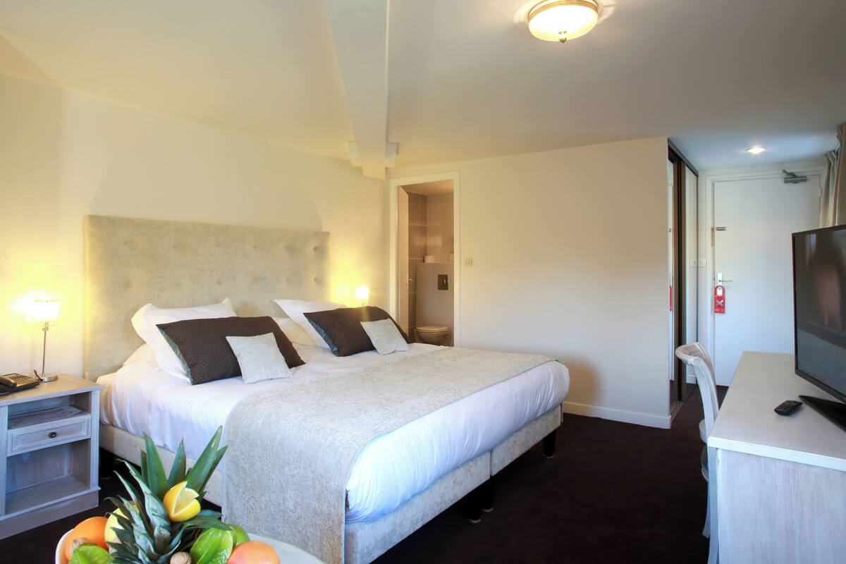 Ein Hotelzimmer mit Bett, Nachttisch, Fernseher und einem kleinen Schreibtisch.
