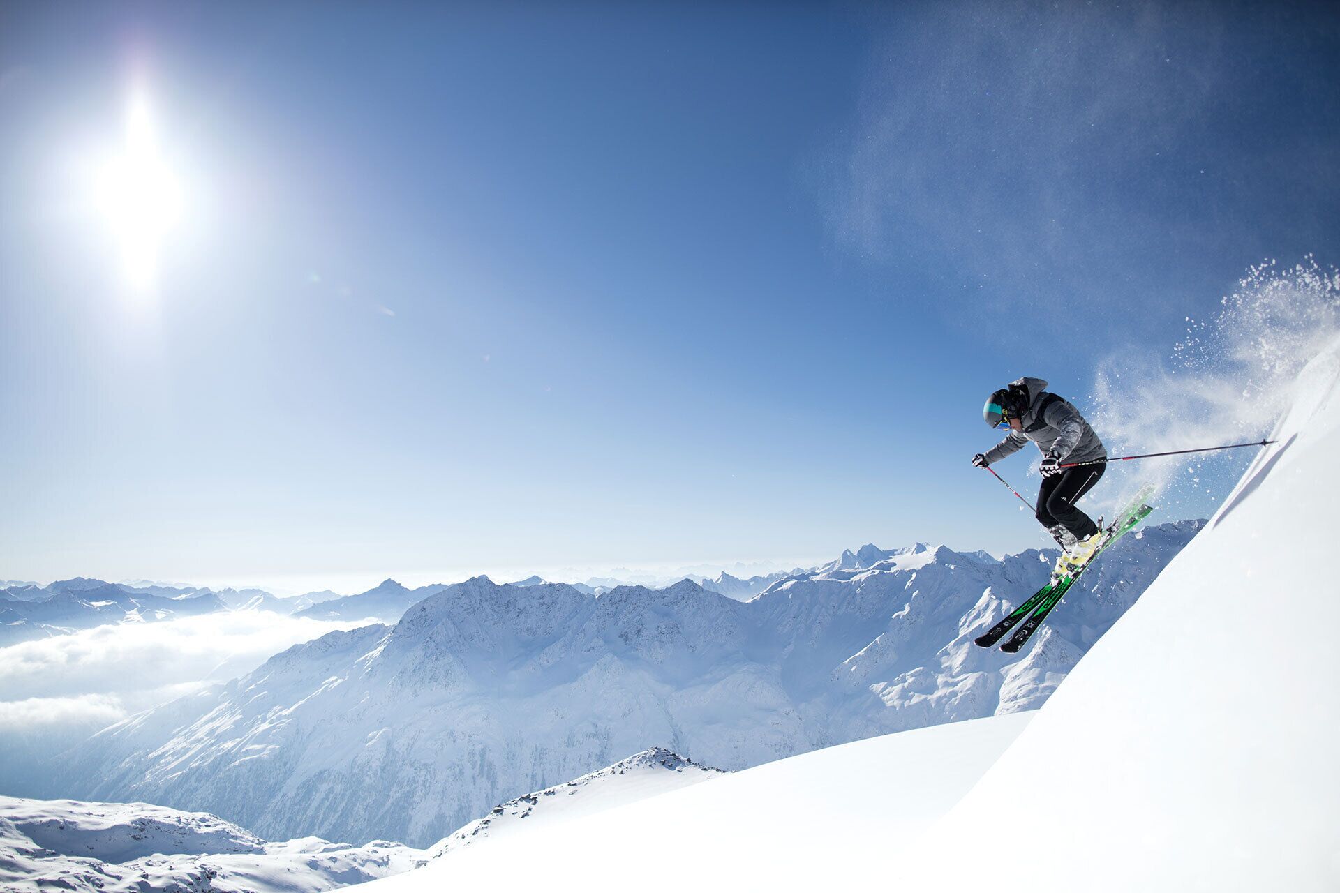 A skier in mid-air performing a jump on a snowy mountain slope.