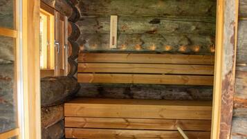 A wooden sauna with a wooden bench and a thermometer on the wall.