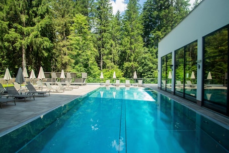 Una piscina techada, una piscina al aire libre, sombrillas
