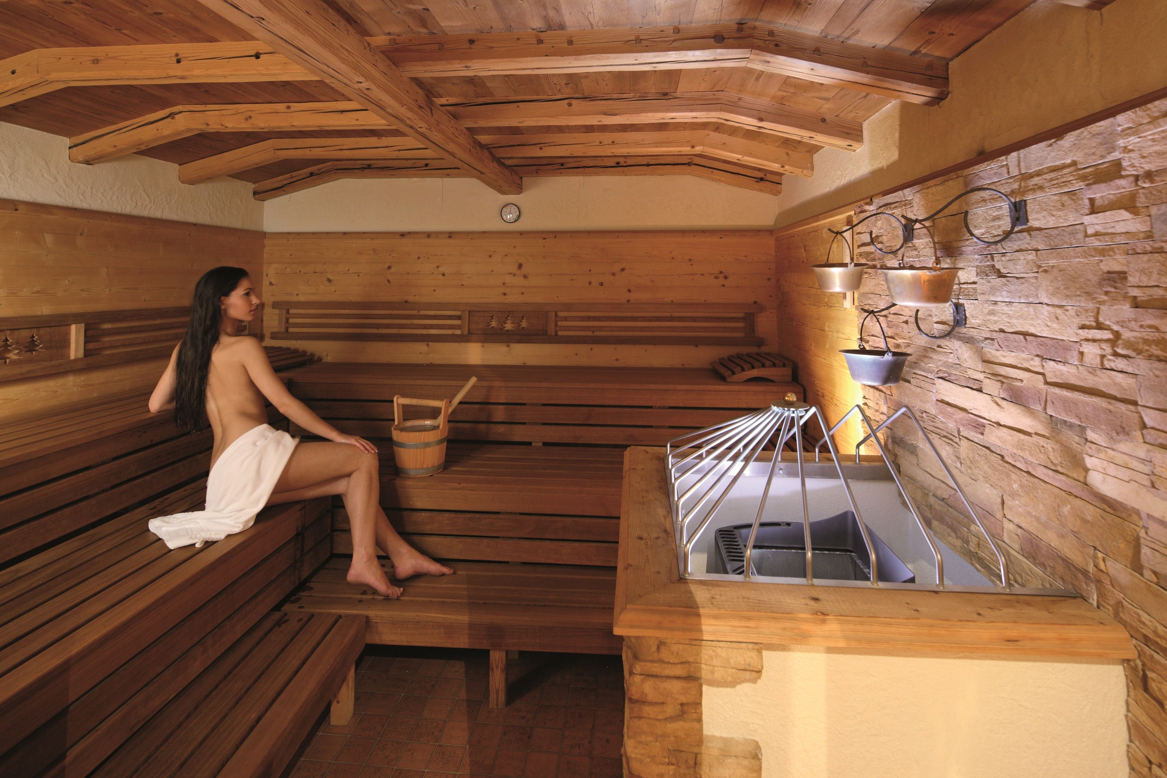 A sauna with wooden benches and a stone wall.