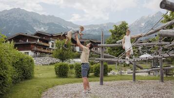 A playground with a rope bridge and a mountainous backdrop.