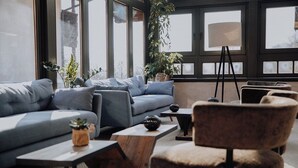A modern living room with a grey sofa, a wooden coffee table, a floor lamp, and a potted plant. - Hotel Kaiser in Tirol (Scheffau am Wilden Kaiser)
