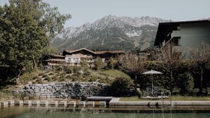 A mountain resort with a swimming pool, stone walls, and wooden buildings. - Hotel Kaiser in Tirol (Scheffau am Wilden Kaiser)