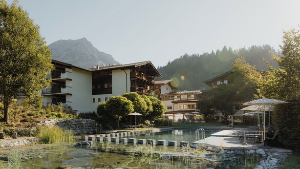 A hotel with a pool, outdoor seating, and mountain views. - Hotel Kaiser in Tirol (Scheffau am Wilden Kaiser)