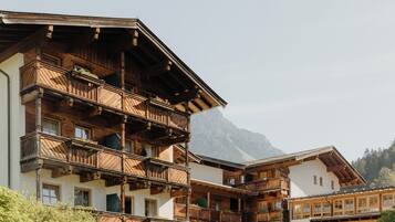 Un chalet tradicional con balcones de madera y montañas al fondo.