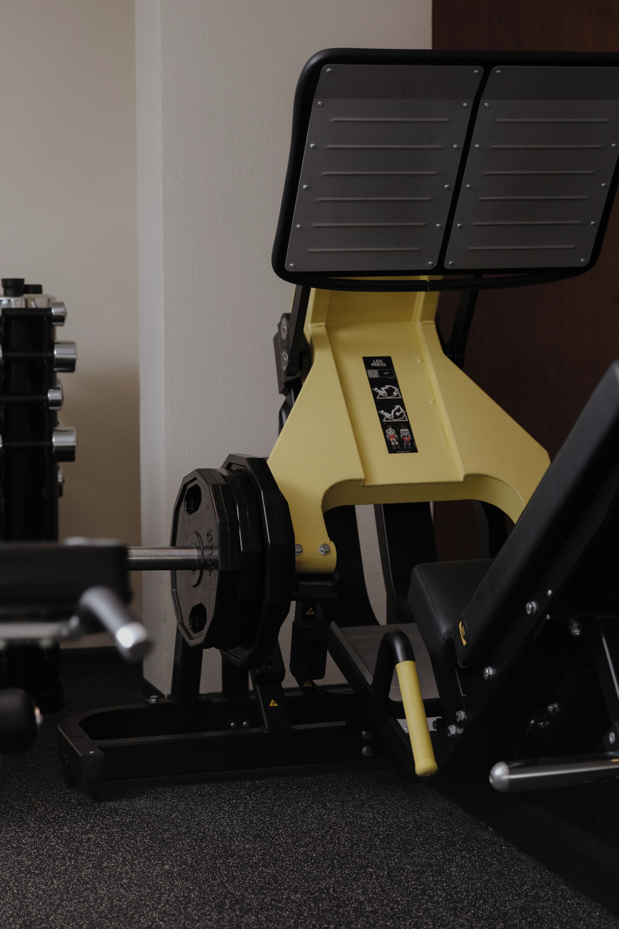A weight bench with a black and yellow color scheme, equipped with a barbell and weight plates.