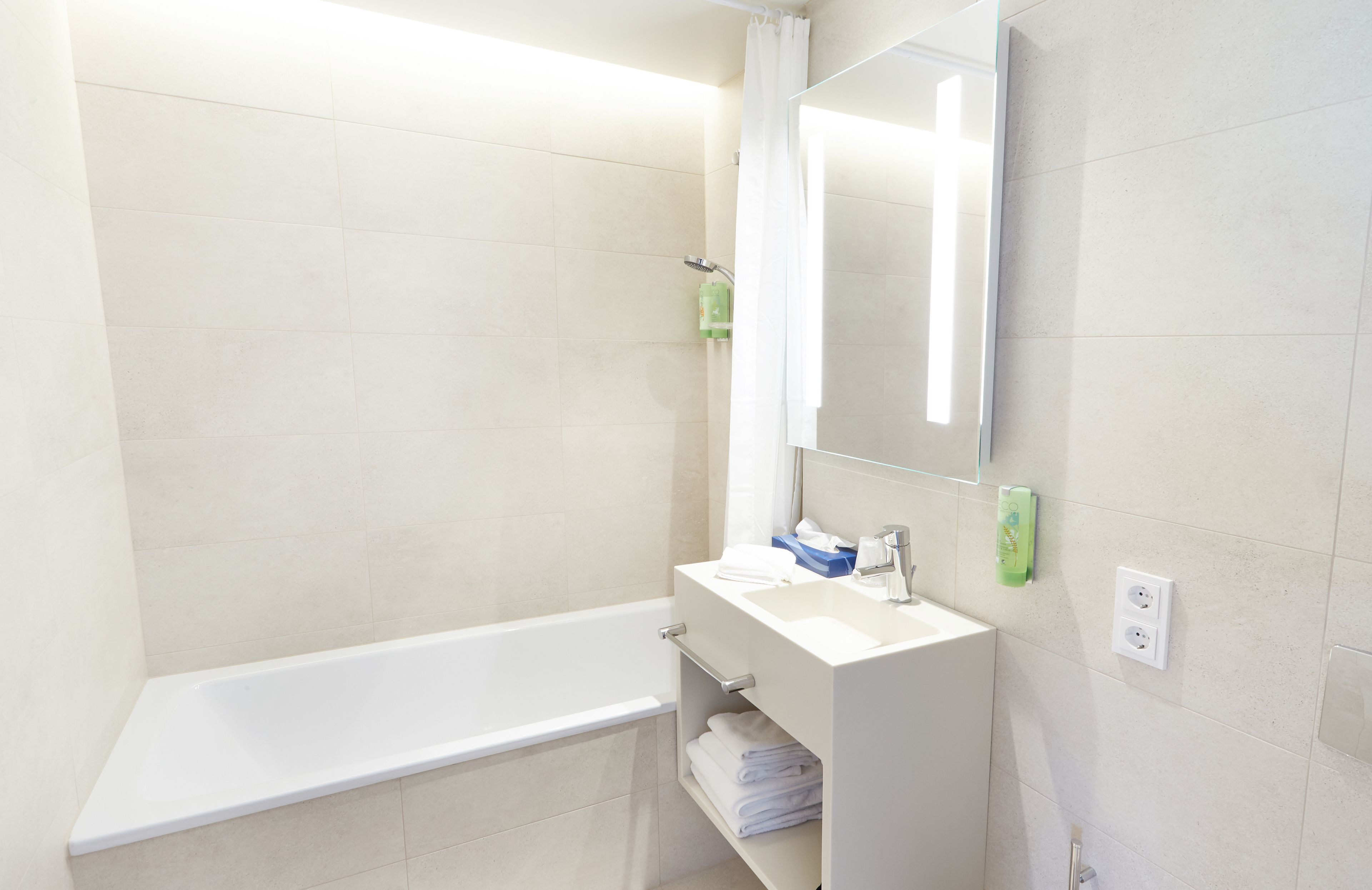 A modern bathroom with a bathtub, a sink, and a mirror.