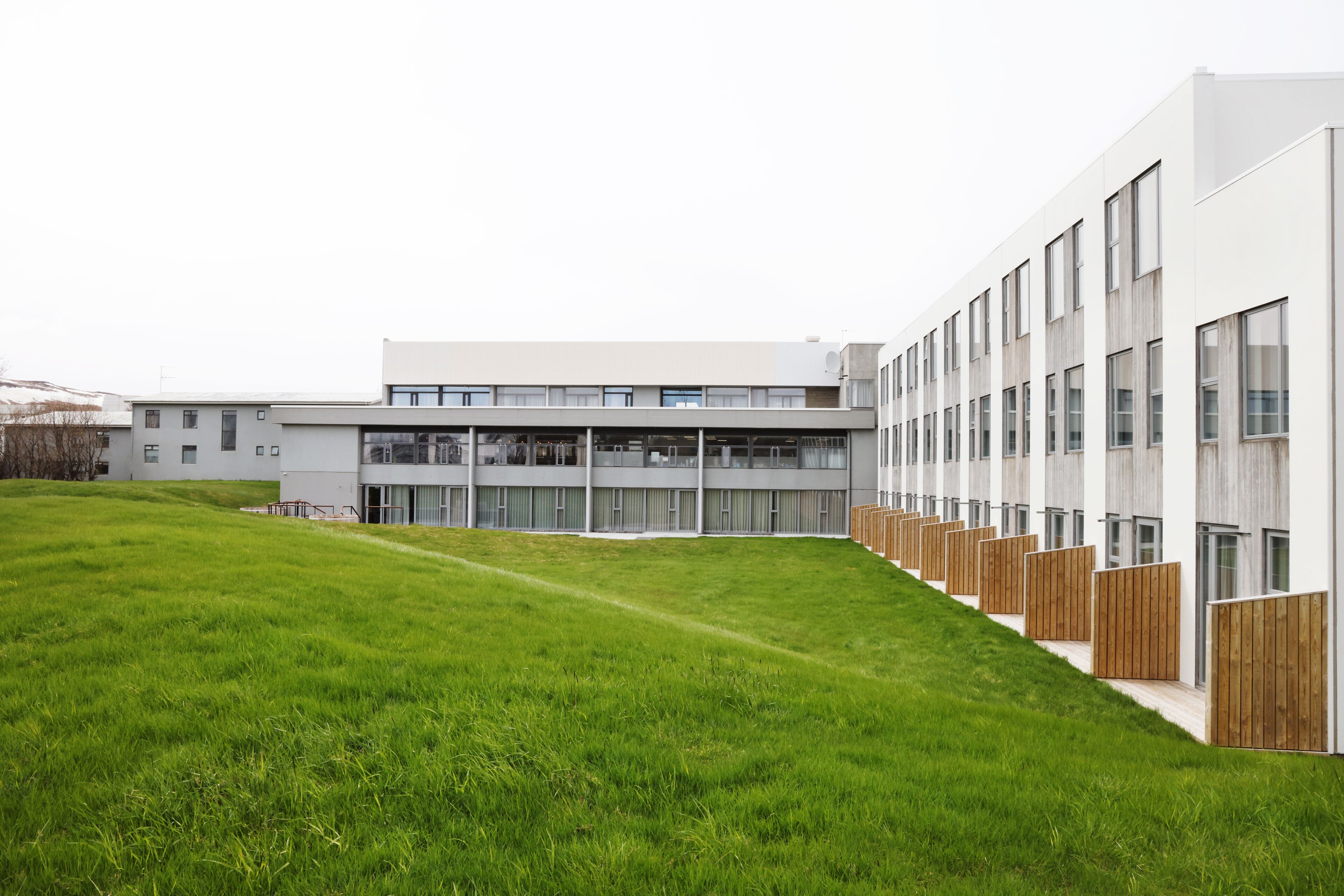 A modern building with a flat roof, large windows, and a grassy courtyard.
