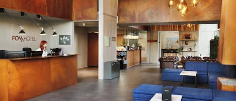 Un hall d’hôtel comprenant un comptoir d’accueil, un espace salon et une petite cuisine.