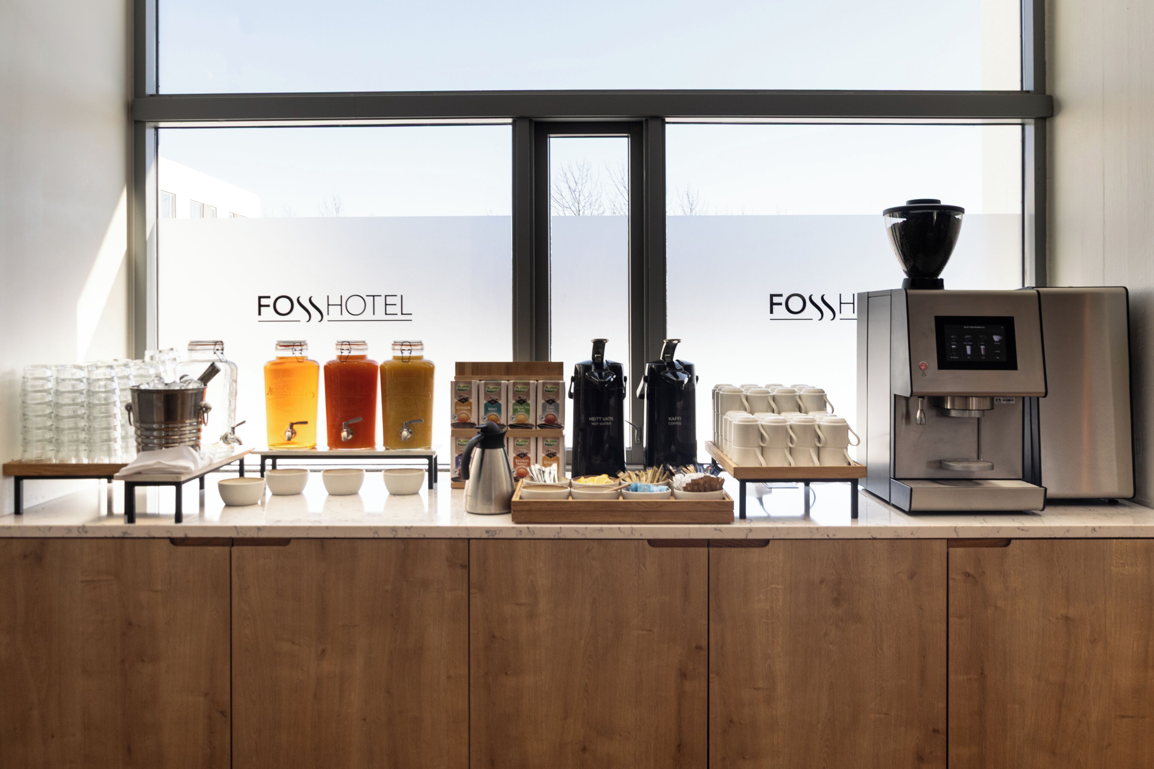 Un espace d’accueil d’hôtel équipé d’une machine à café, d’un coin pour préparer le thé et de différents distributeurs de boissons.