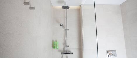 A modern shower with a handheld showerhead and a fixed showerhead, a handheld shower attachment, and a wall-mounted control panel.