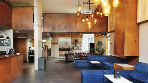 A spacious lobby with a reception desk, blue seating area, and a modern chandelier. - Fosshotel Reykholt (Borgarbyggd)