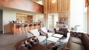 A modern lounge area with leather sofas, a bar, and a bookshelf. - Fosshotel Reykholt (Borgarbyggd)