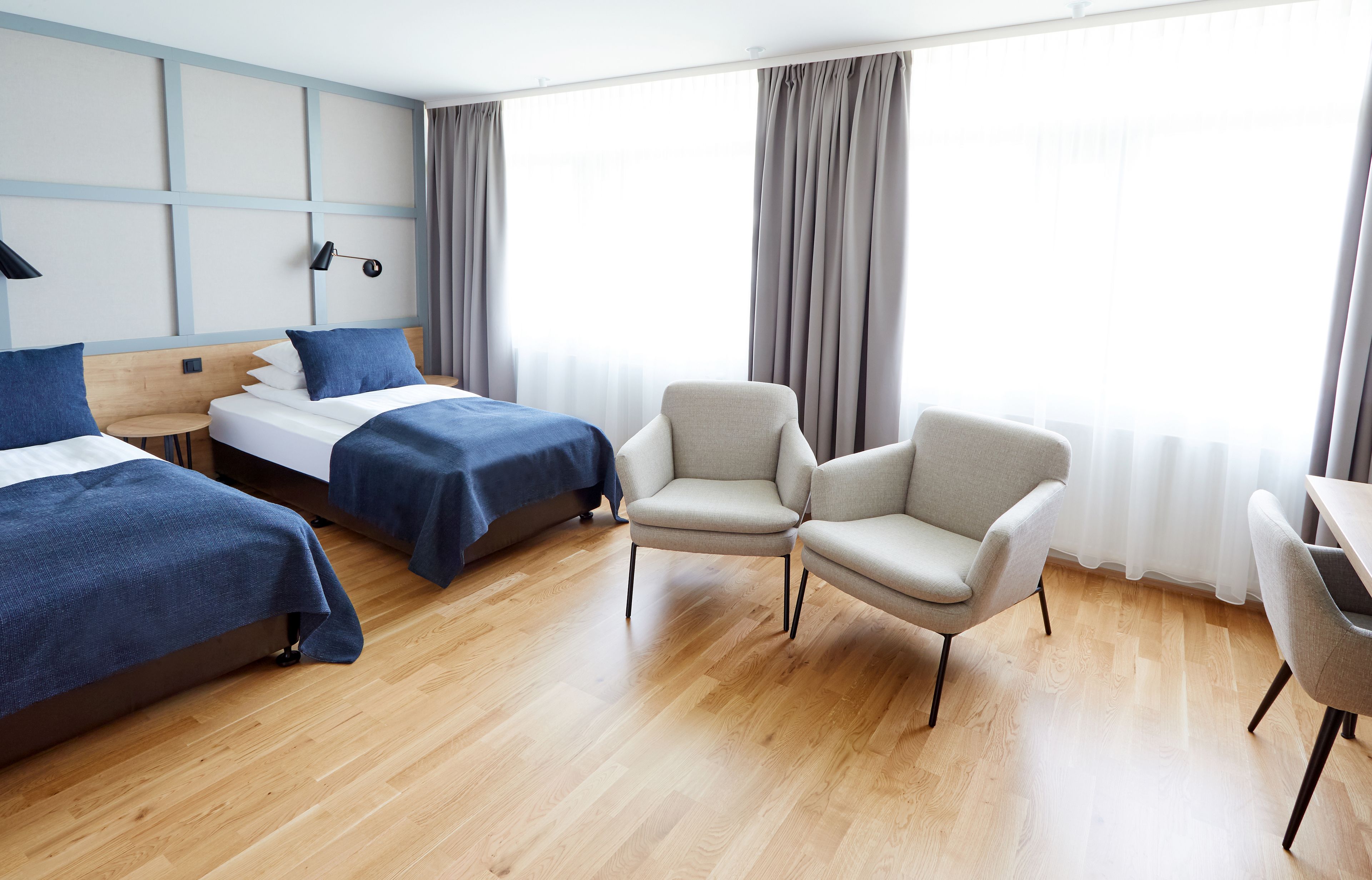 A hotel room with two beds, a desk, and two chairs.