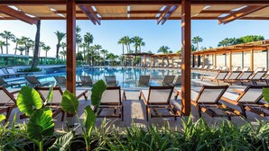 A poolside area with lounge chairs and palm trees. - Sural Saray Hotel - All inclusive (Manavgat)