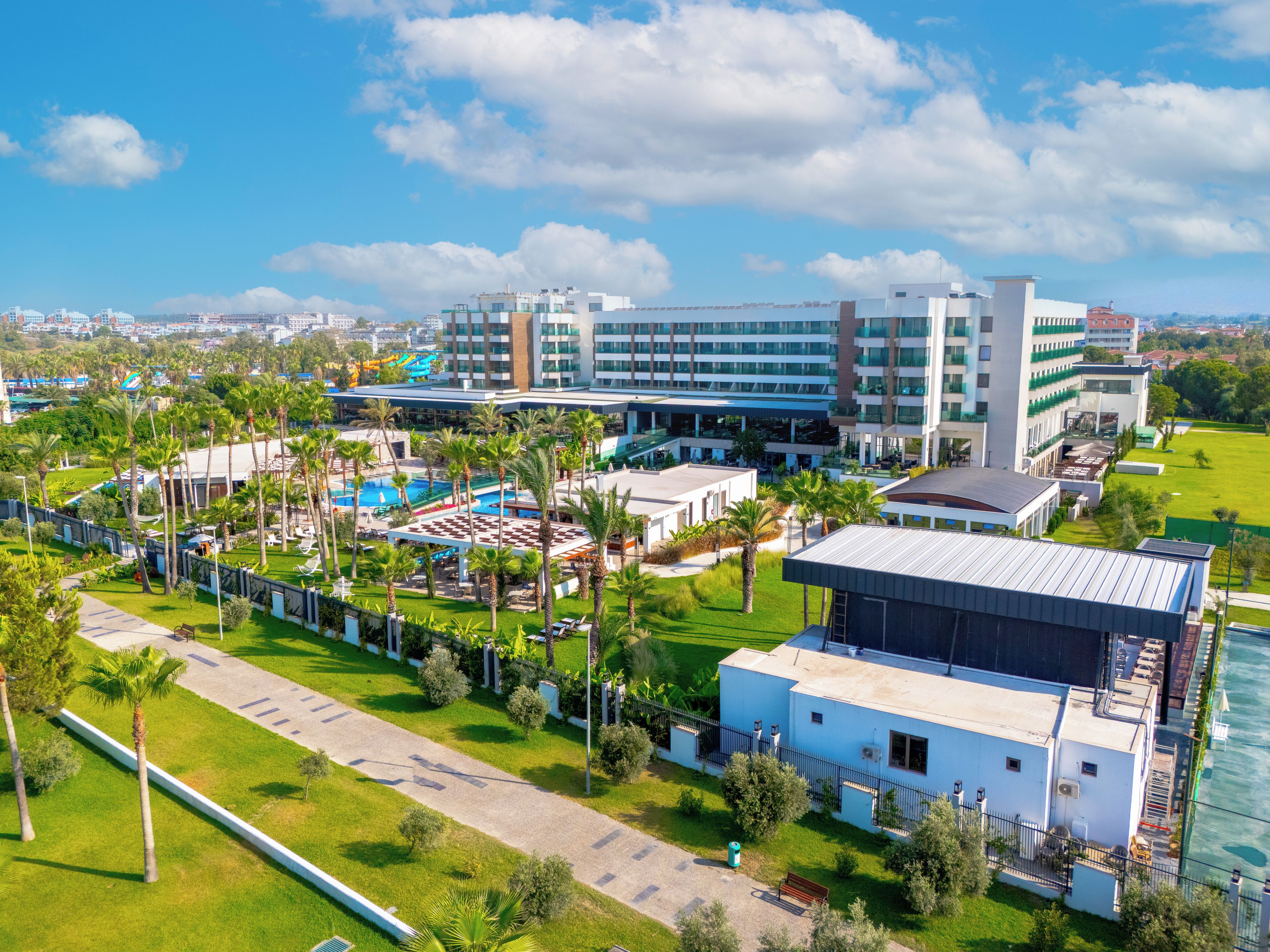 A hotel with multiple buildings, a swimming pool, and palm trees.