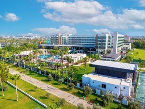 Ein Hotel mit mehreren Gebäuden, einem Schwimmbad und Palmen.