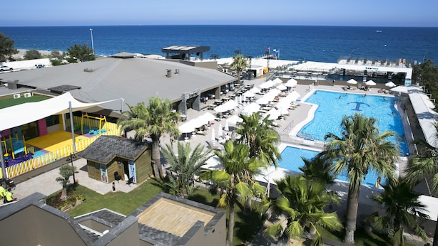 A resort with a large swimming pool, outdoor seating, and a view of the ocean. - Sailor's Beach Club - All Inclusive (Kemer)