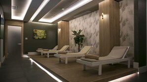 A spa area with three white sun loungers, a green wall with a leaf pattern, and a painting of a face. - Sailor's Beach Club - All Inclusive (Kemer)