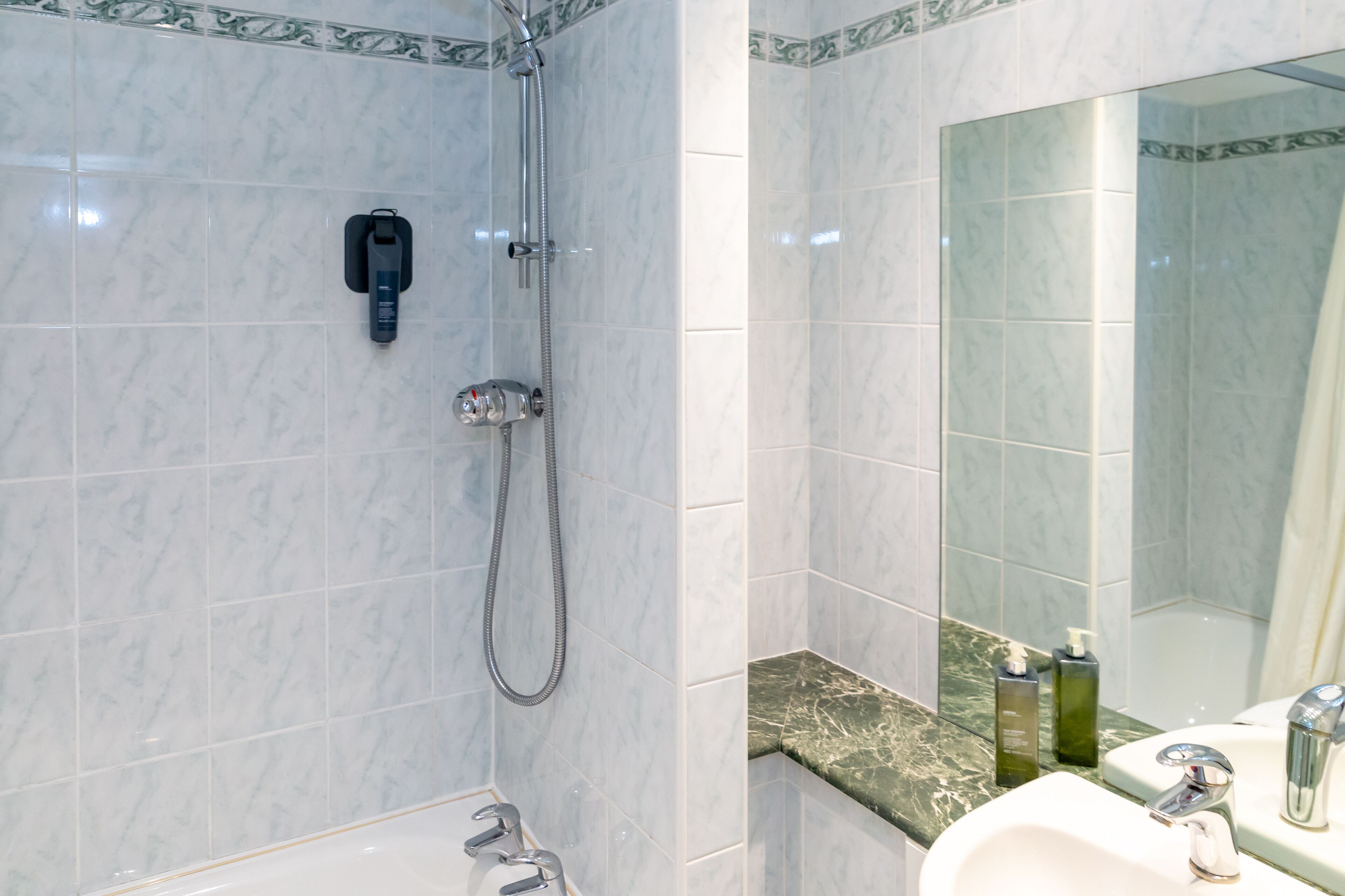 A bathroom with a shower, a sink, and a mirror.