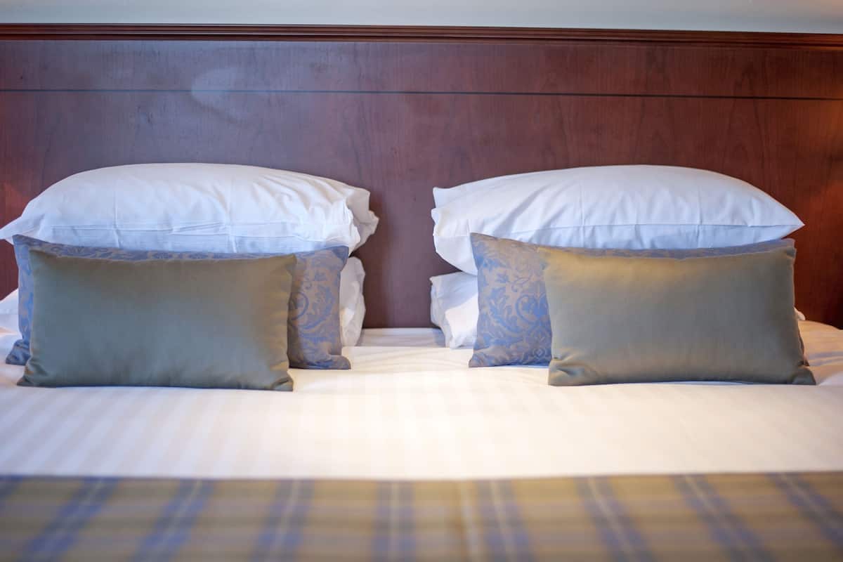 A double bed with white pillows and two decorative pillows with blue patterns.