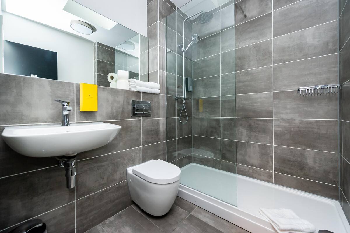 Un baño moderno con lavamanos, inodoro y ducha con mampara de vidrio.