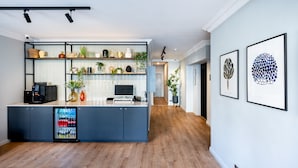 Una cocina moderna con un refrigerador empotrado, una cafetera y varios objetos decorativos en estantes.