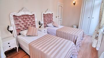 Une chambre d’hôtel avec deux lits, chacun recouvert d’une couvre-lit à rayures, une table de chevet blanche, une petite table et un miroir.