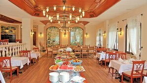 A spacious dining area with multiple tables set for a buffet, wooden flooring, and a large chandelier. - Aspen Hotel - Special Class (Antalya)
