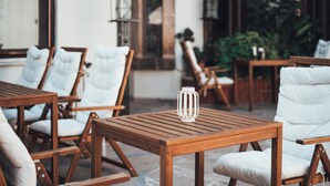 An outdoor seating area with wooden tables and white cushioned chairs. - Aspen Hotel - Special Class (Antalya)