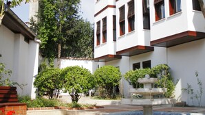 A multi-story building with a white facade and brown trim, surrounded by greenery and a fountain. - Aspen Hotel - Special Class (Antalya)