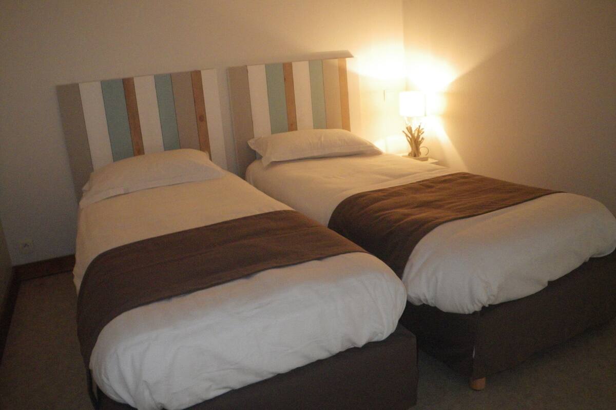 A double bed with a striped headboard, a bedside table with a lamp, and a brown throw blanket.