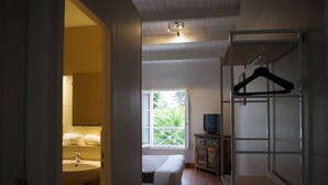 A bedroom with a bed, a window, a TV, a cabinet, and a hanging rack. - Appart'hôtel Perle de Ré (La Couarde-sur-Mer)