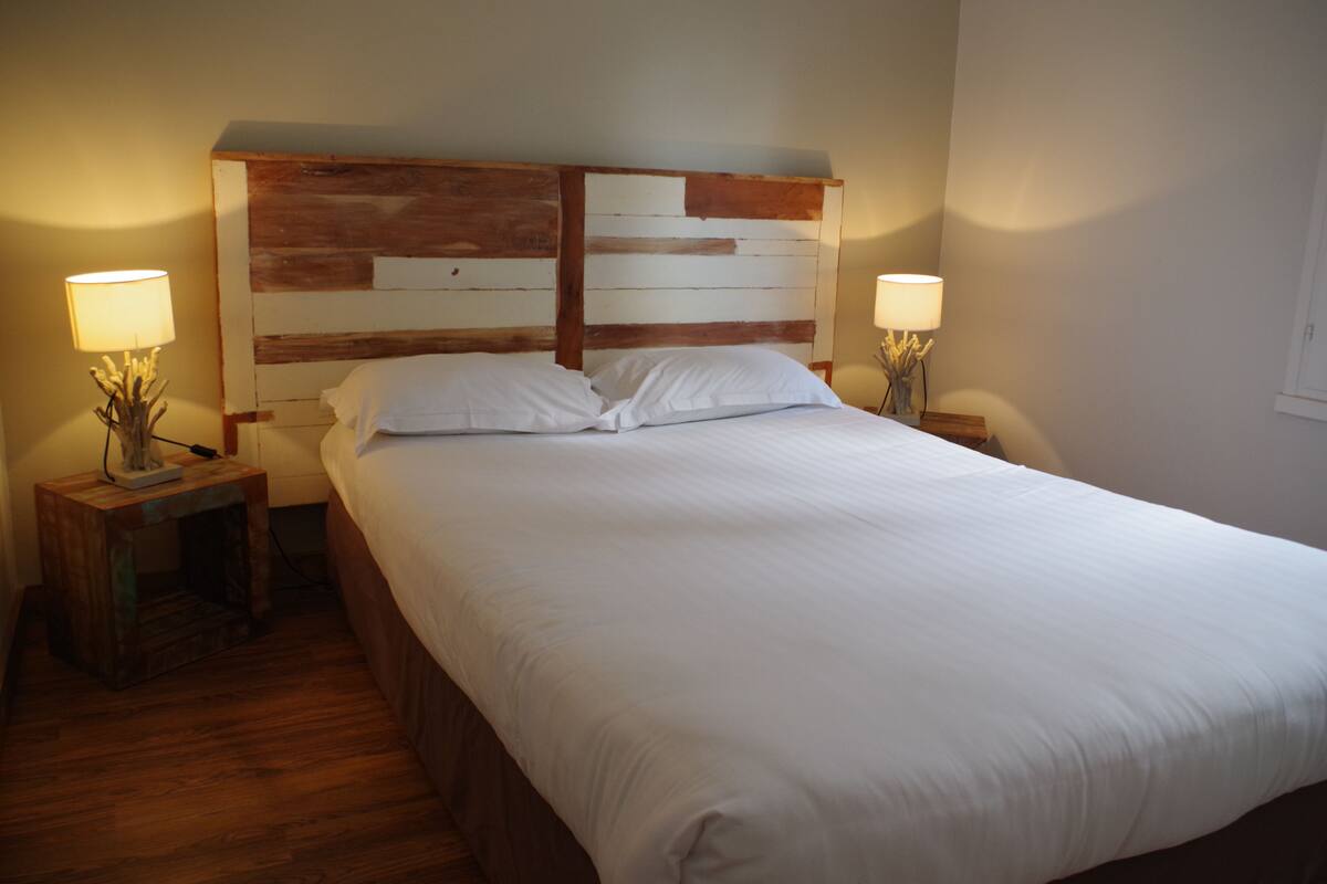 A neatly made bed with white linens in a room with wooden headboard and nightstands.
