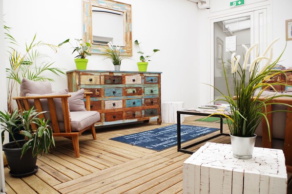 A cozy room with a wooden floor, a wooden chair with cushions, a colorful dresser, and several potted plants. - Appart'hôtel Perle de Ré (La Couarde-sur-Mer)