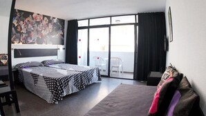 Une chambre d’hôtel comprenant un lit, un canapé, une table à manger et un balcon avec des chaises.