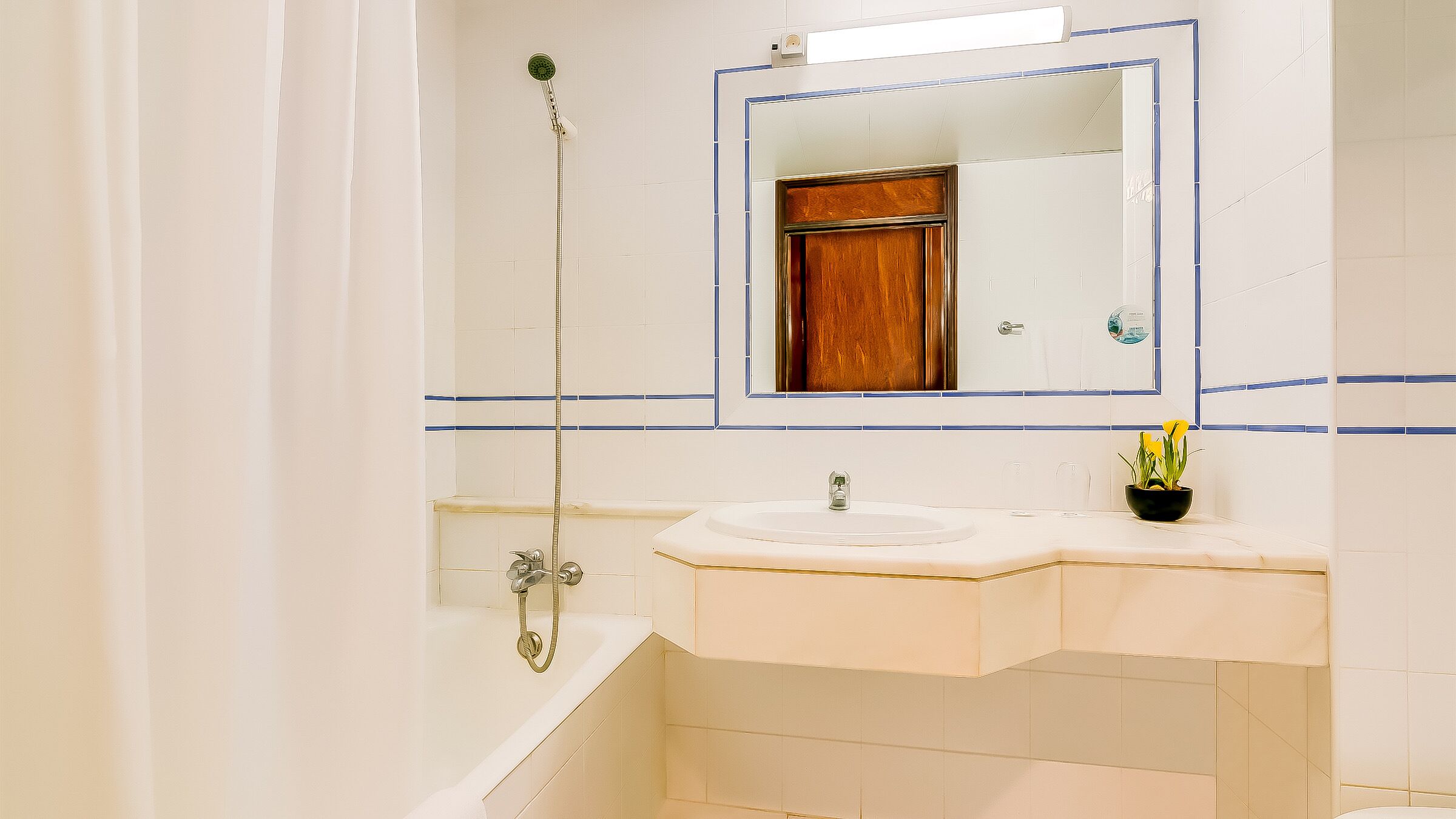 Un baño con bañera, lavamanos, espejo y ducha.