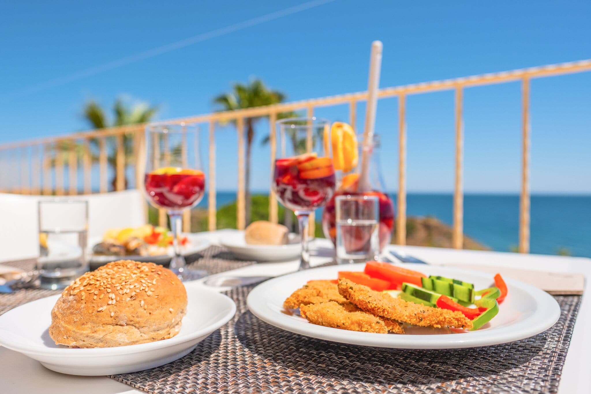 A table set with food and drinks, overlooking a scenic ocean view.
