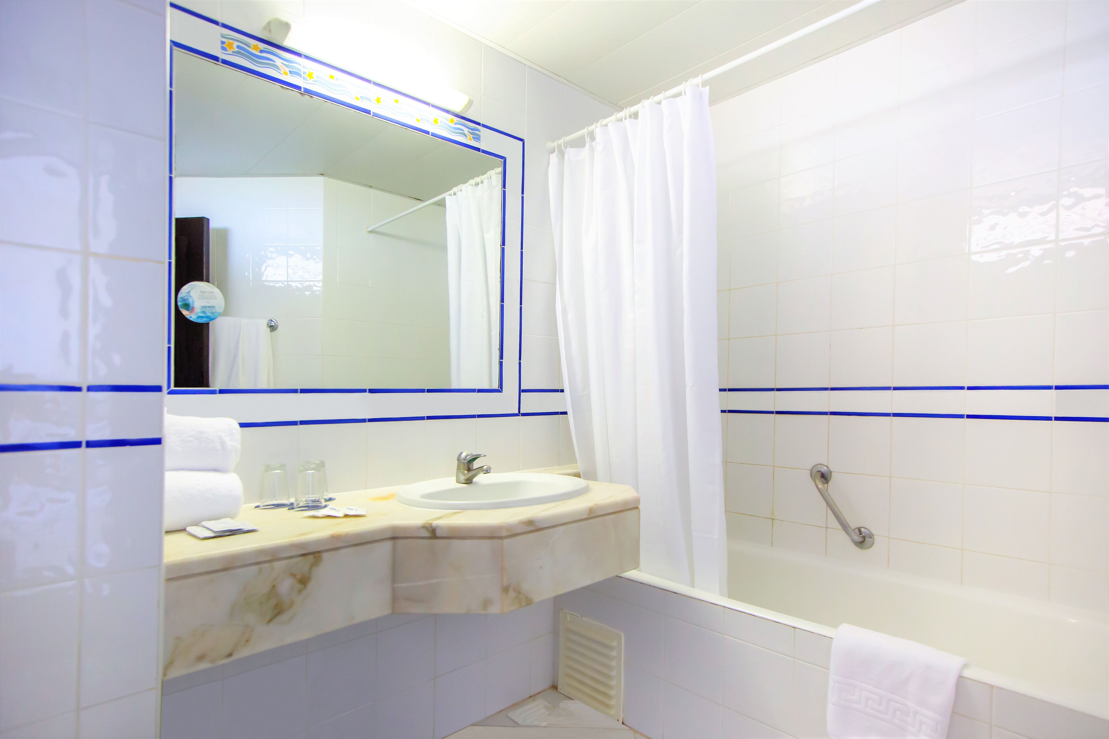 A bathroom with a sink, mirror, and shower.