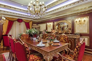 Un comedor formal con una gran mesa de madera, sillas ornamentadas y una araña.