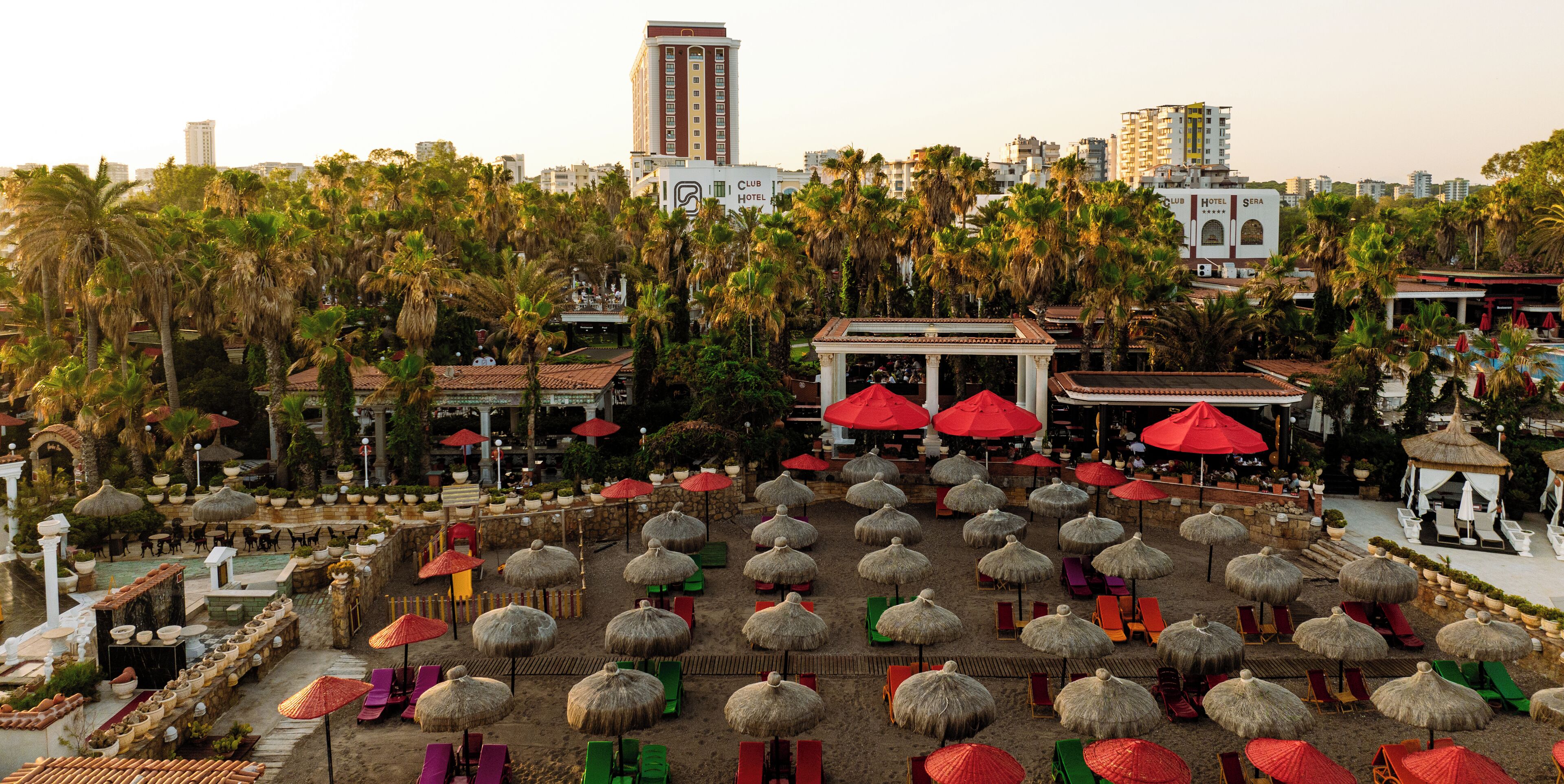 A beachside resort with thatched umbrellas, lounge chairs, and a view of the city skyline.