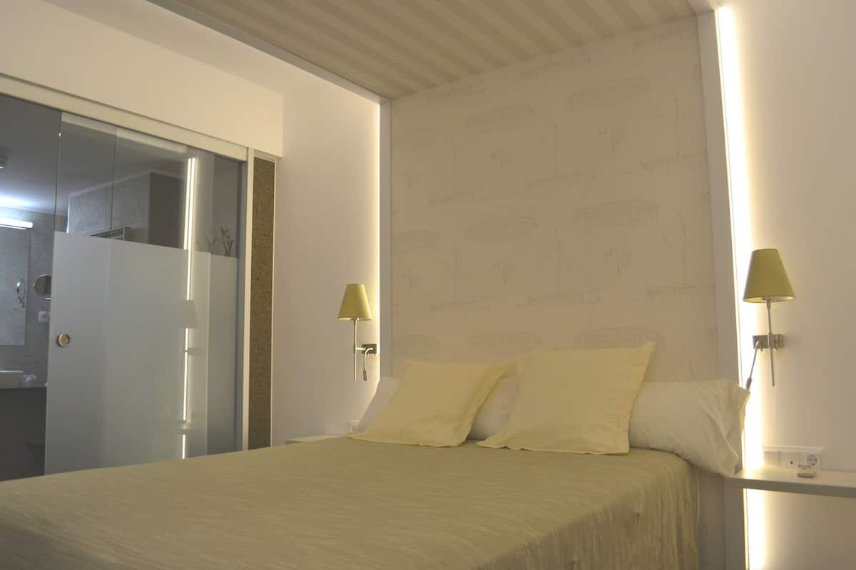 A bedroom with a bed, two bedside lamps, a door, and a wall with a pattern.