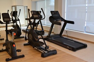Un gimnasio con varios equipos de ejercicio, incluyendo cintas de correr y bicicletas estáticas.