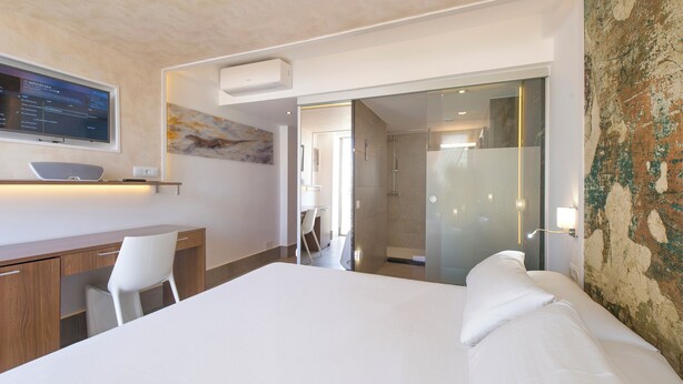 A modern hotel room with a large bed, a desk, a chair, and a shower area. - Hotel Marfil (Sant Antoni de Portmany)